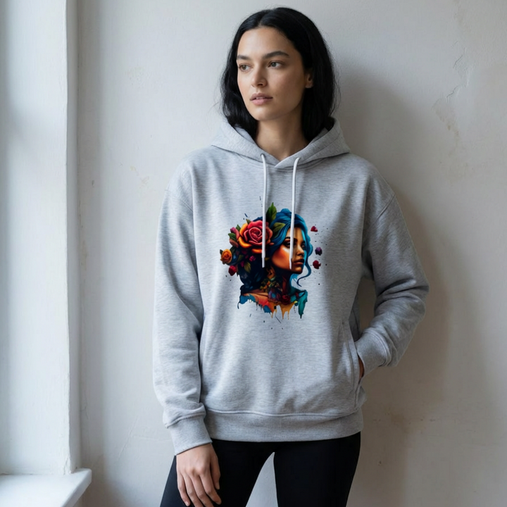 Woman wearing a gray hoodie with a colorful floral design, standing against a white wall.